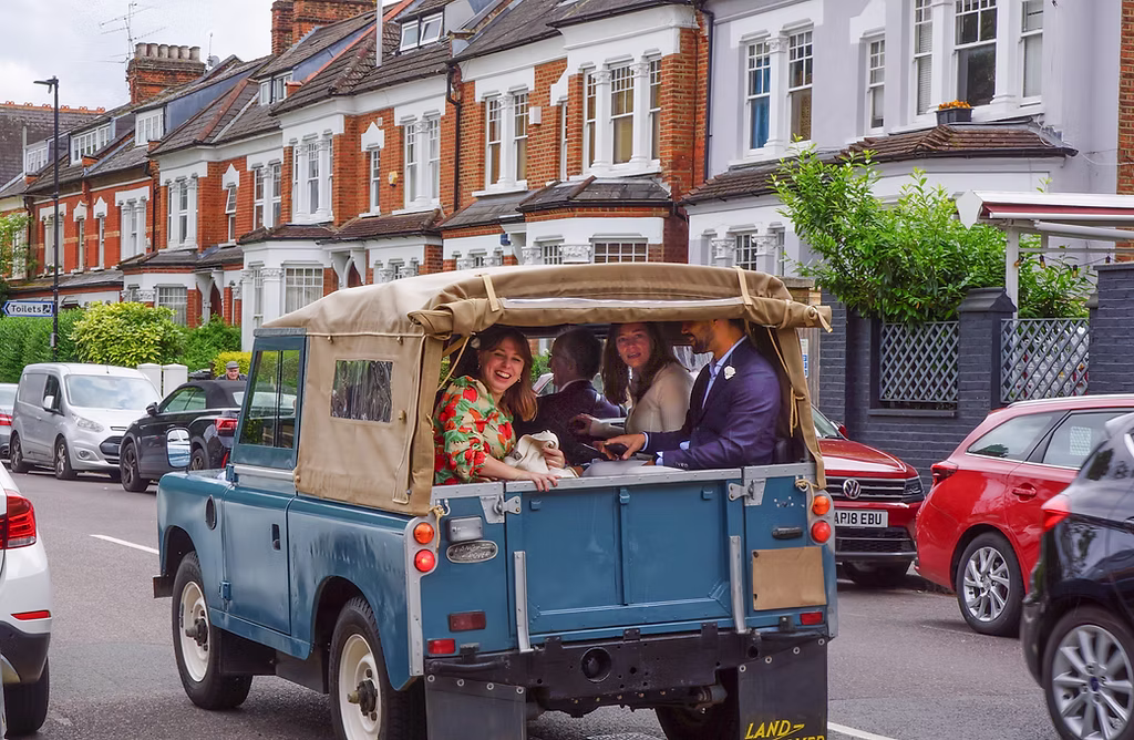 Wedding party laughing in the back of an EV Classics Series 2A on a north-London street